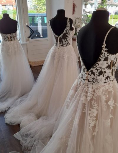Drei Mannequins zeigen Brautkleider mit Spitze